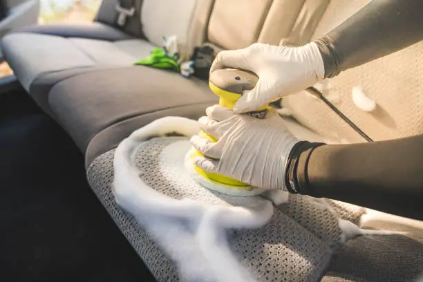 A Man Cleaning Car Interior By Use Foam Chemical And Scrubbing Machine.