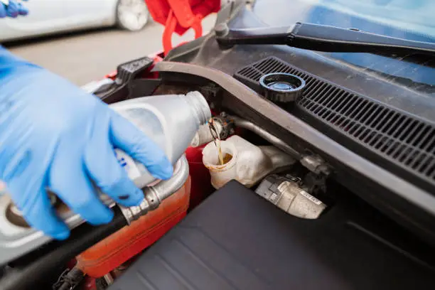 Close Up Of An Unrecognisable Young Caucasian Man Adding Brake Fluid To A Car.